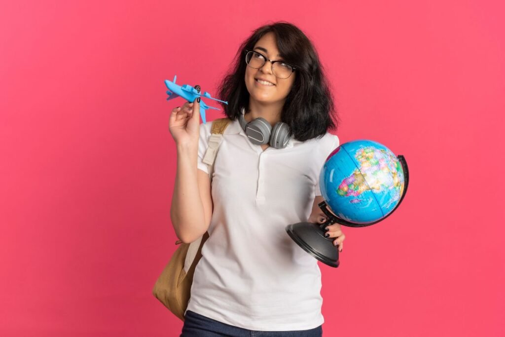 student carrying a blue plane and a globe in her both hands looking happy because she is willing to study abroad