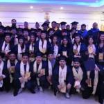 Graduating students in academic gowns holding certificates at a Texas International College convocation ceremony