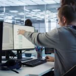 two men looking and pointing at the computers