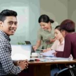 A happy young man sitting in a classroom with some other students learning a best IT Course in Nepal